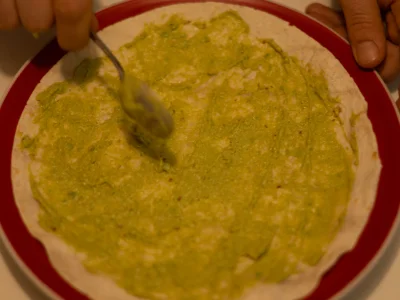Ătalez une galette de fajitas et garnissez-la gĂ©nĂ©reusement de purĂ©e d'avocat.