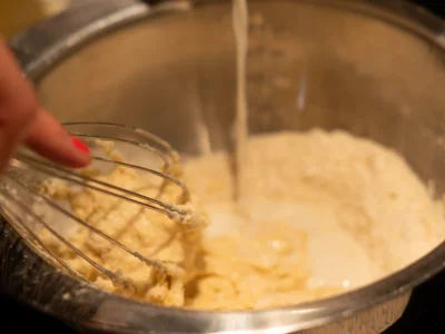 Ajoutez peu à peu le lait, en remuant avec un fouet, pour éviter les grumeaux. Incorporez le beurre fondu et mélangez bien.