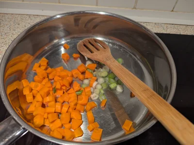 Faites chauffer un filet d'huile de tournesol dans une casserole à feux moyen-vif. Faites-y revenir le blanc de l'oignon nouveau et les dés de carottes pendant 3-4min.
